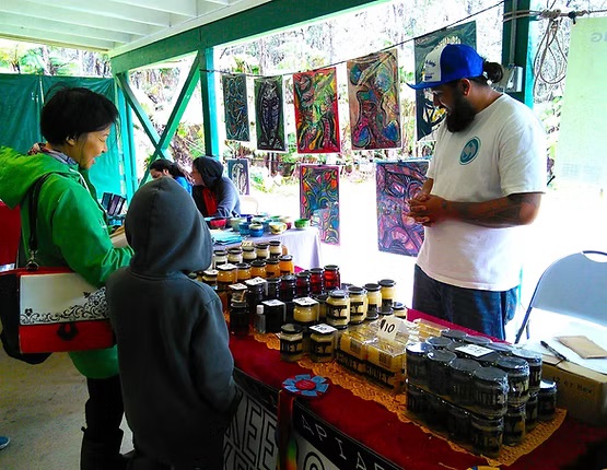 A vendor sells handcrafted goods to a family at Sunday Farmer's Market in Volcano.
